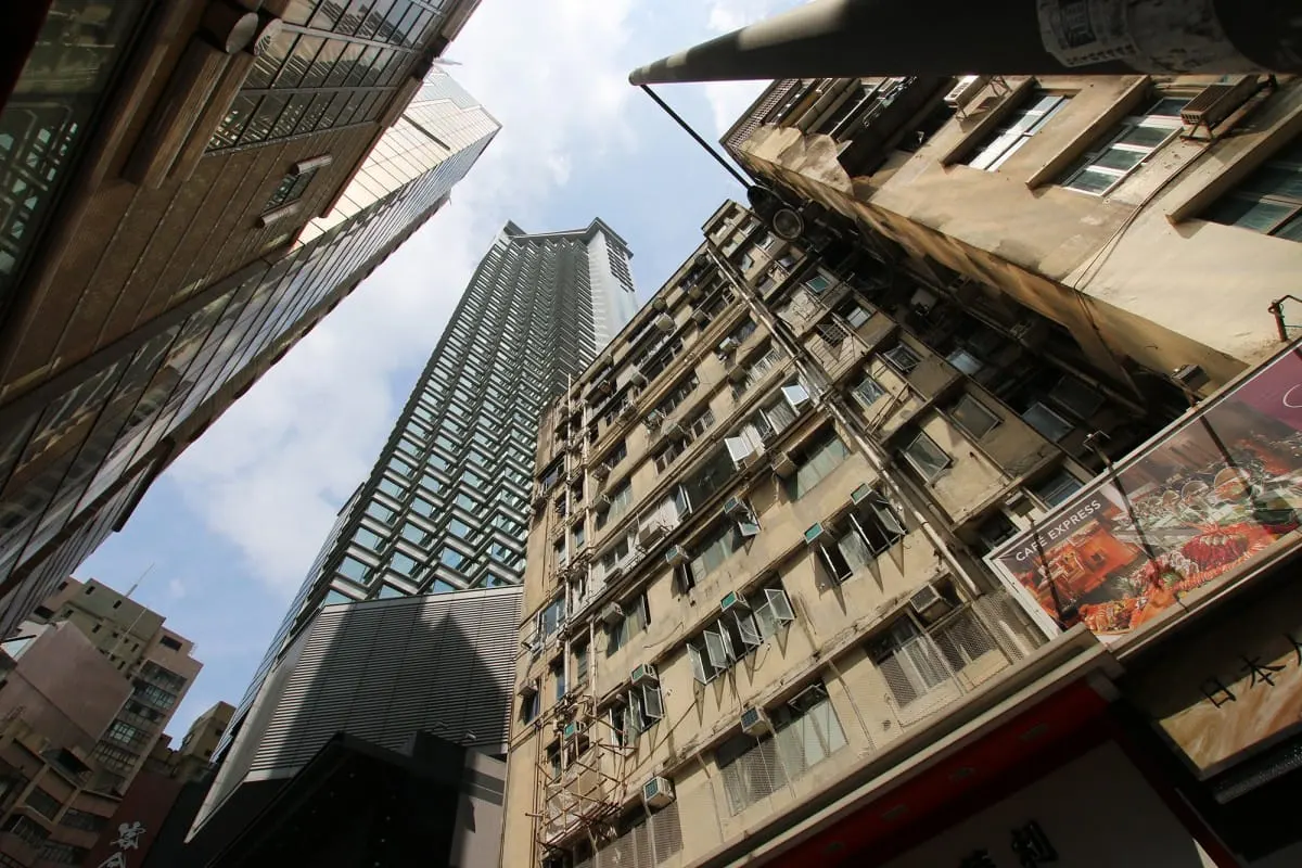 Looking up at towering old apartment blocks and glass skyscrapers in Hong Kong
