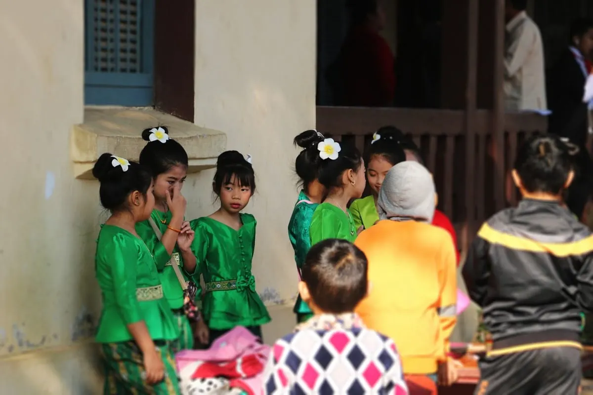 Schoolgirls in green traditional dress with flowers in their hair, Luang Prabang