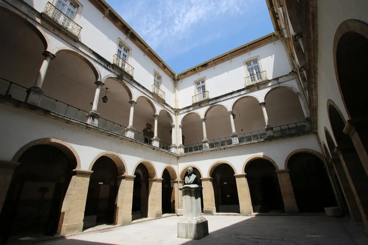 Arcaded two-story atrium of the University of Coimbra law school with a bust