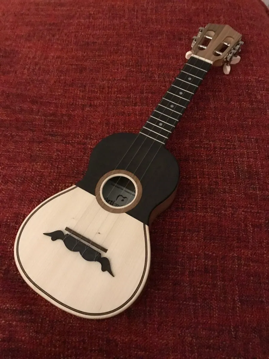 Small four-string Portuguese cavaquinho lying on a red fabric surface