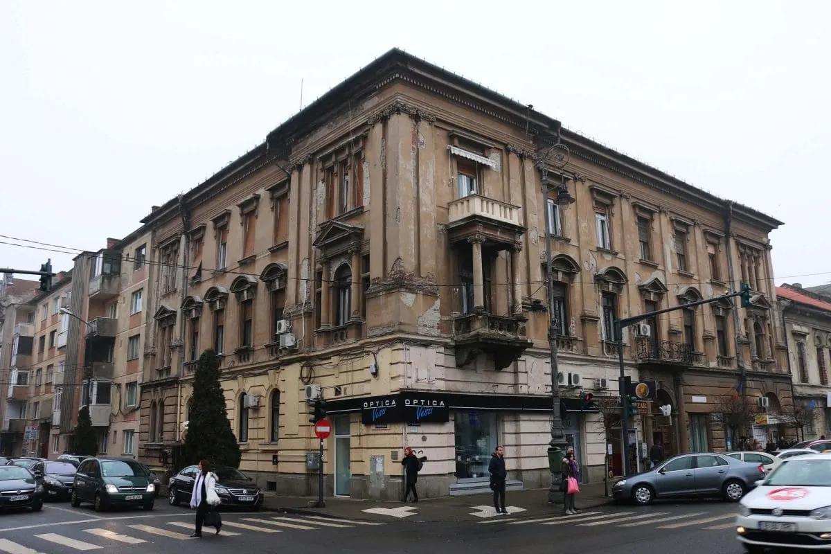 Faded ornate corner building at a street crossing in Arad