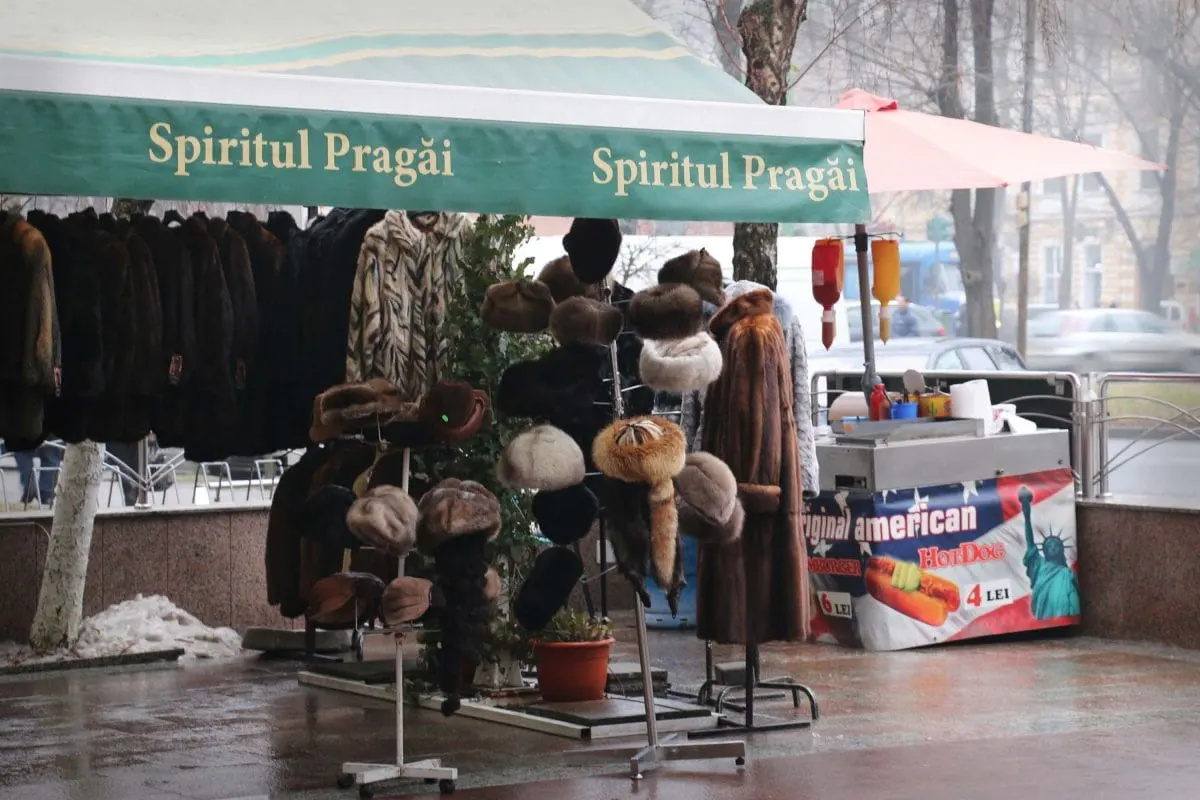 Fur coats and hats for sale beside a hot dog stand