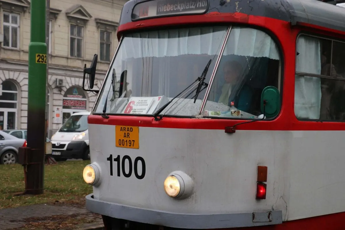 Red and white tram with Arad plate and a driver