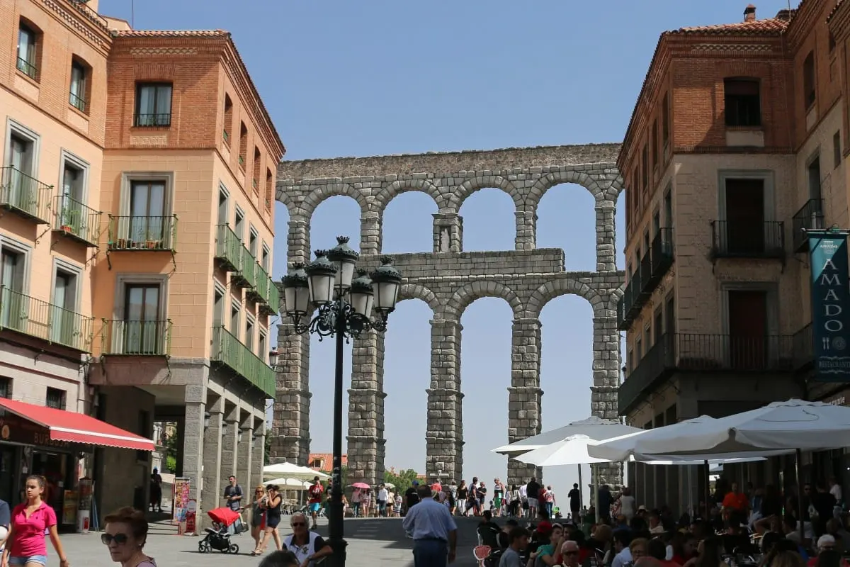 Roman aqueduct of Segovia framed by buildings and cafe umbrellas