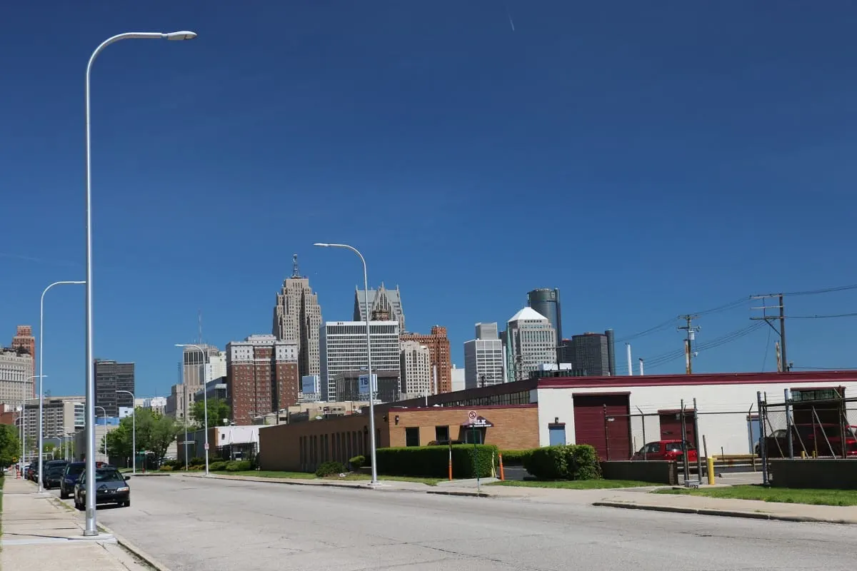 Downtown Detroit skyline seen down a wide street under a clear blue sky