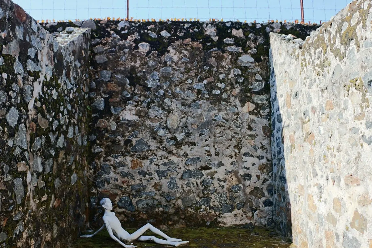 Statue of a prisoner slumped in a stone-walled open-air cell, Con Dao